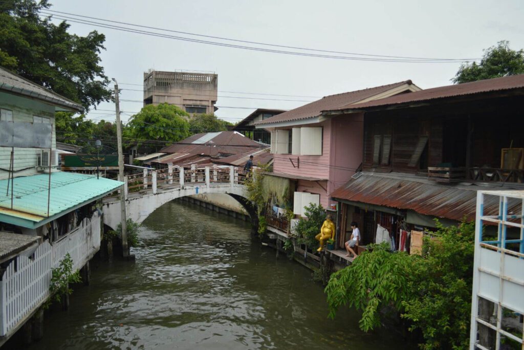 locals sitting and chatting along the Saen Saep Canal Bangkok near traditional wooden homes