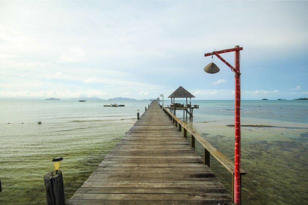 Jetty on Koh Mak’s beach, ideal for oyster fishing, with calm turquoise waters and a clear sky.