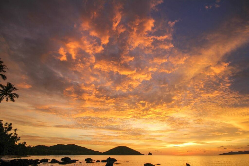 Stunning orange sunset over Koh Mak’s beach, with vibrant skies reflecting on calm turquoise waters.
