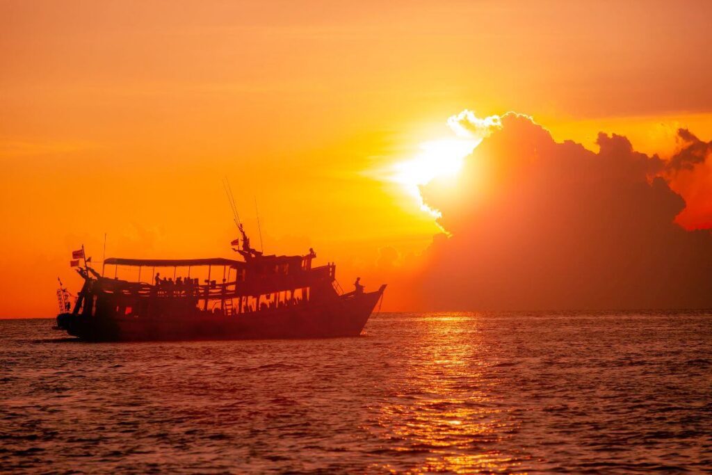 Sunset view of a scuba diving boat in Koh Tao’s sea, surrounded by calm waters and a vibrant orange sky.