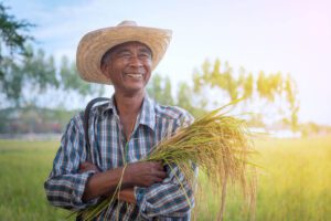 Thai farmer smiling warmly in the fields, representing rural life and agricultural traditions.