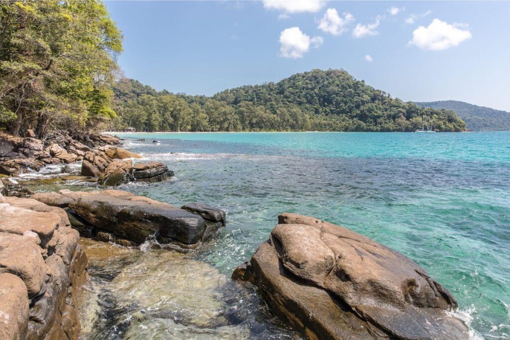 quiet tropical rock beach with soft waves and a simple tree line