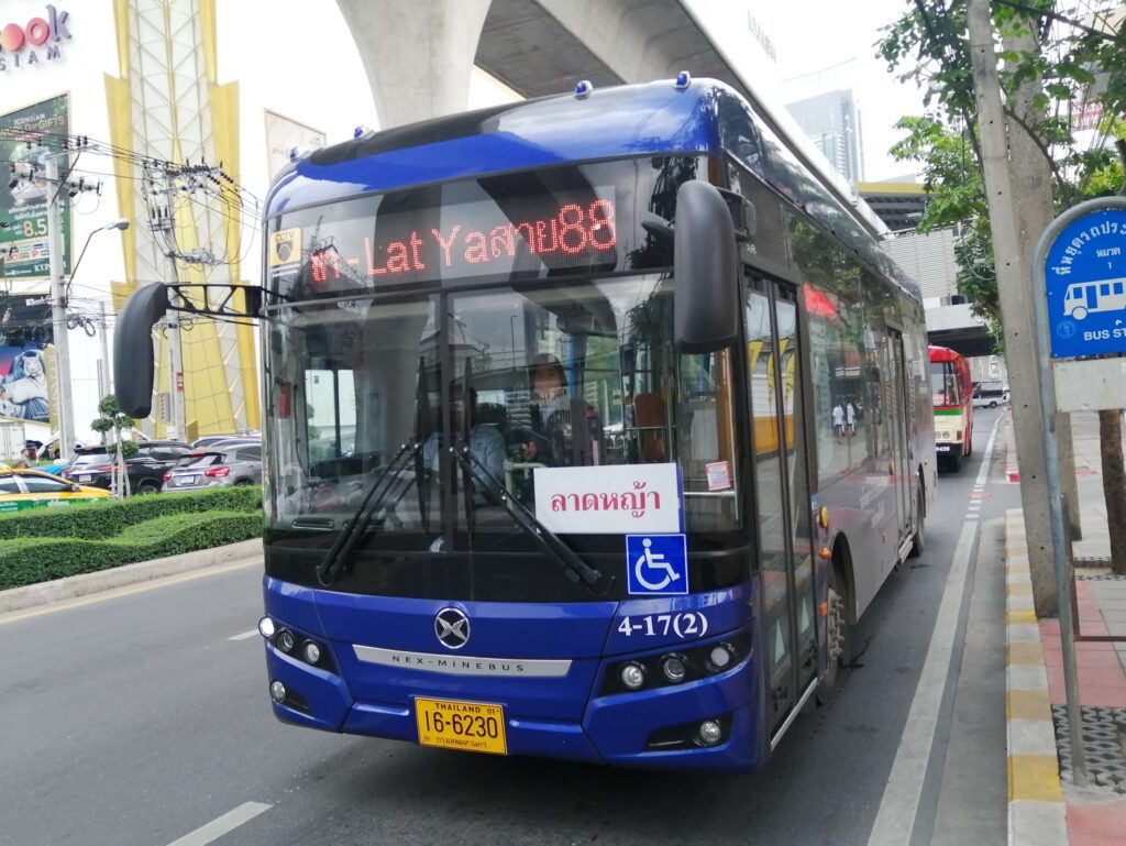 Modern electric blue bus driving on a street while getting around Bangkok.