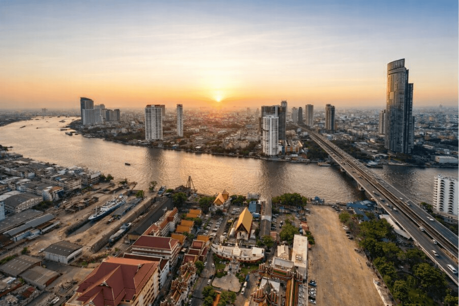 Bangkok riverside crossing with local boats and city skyline
