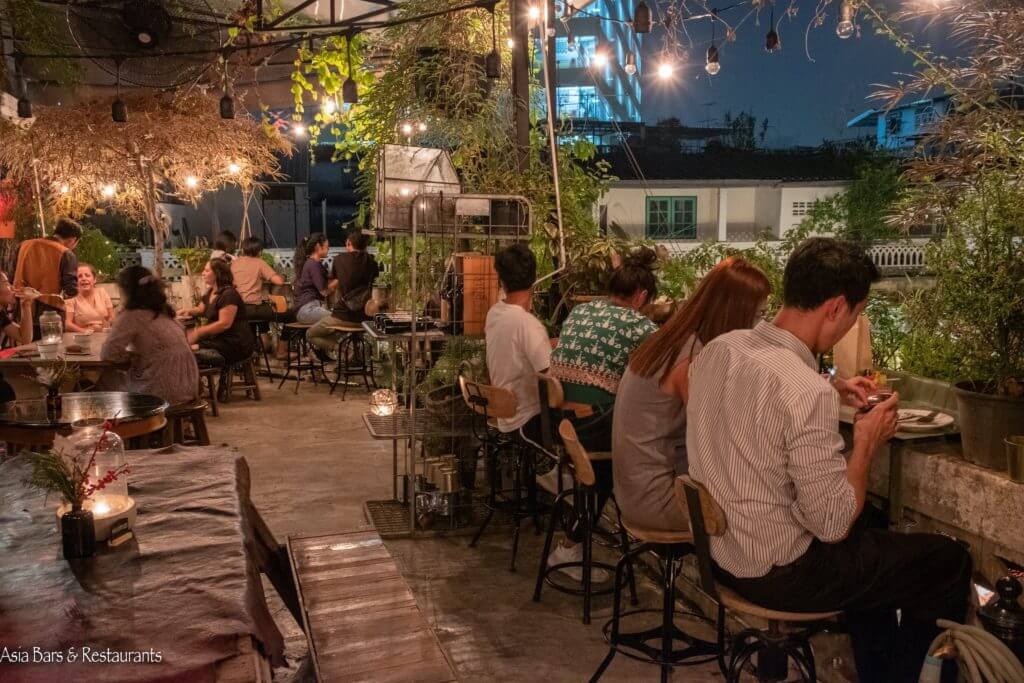 Wallflowers Café rooftop in Bangkok with plants, warm lighting, and a cozy terrace vibe in Chinatown Soi Nana