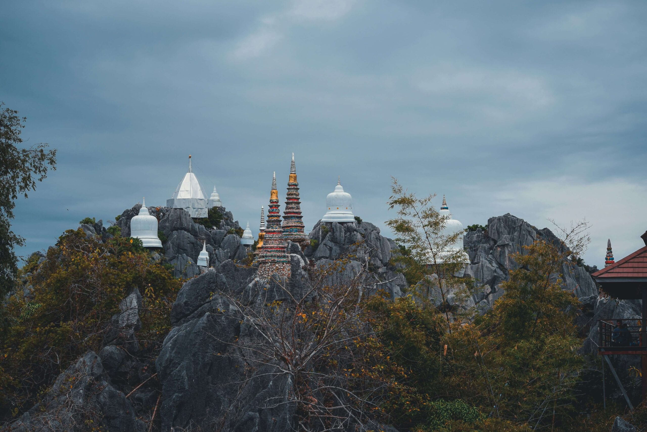White and gold chedis on a limestone peak at Wat Chaloem Phra Kiat, Lampang